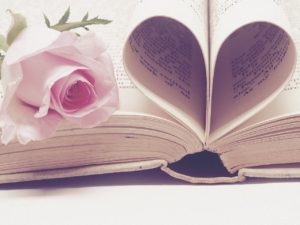 open book with pages folded into a heart, with a pink rose