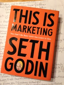 cover of book "This Is Marketing" which is mostly text, with a face in one letter
