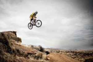 a mountain biker leaping off a rock