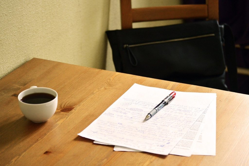 papers with red pen on table, with coffee