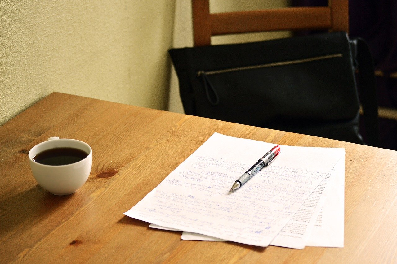 papers with red pen on table, with coffee